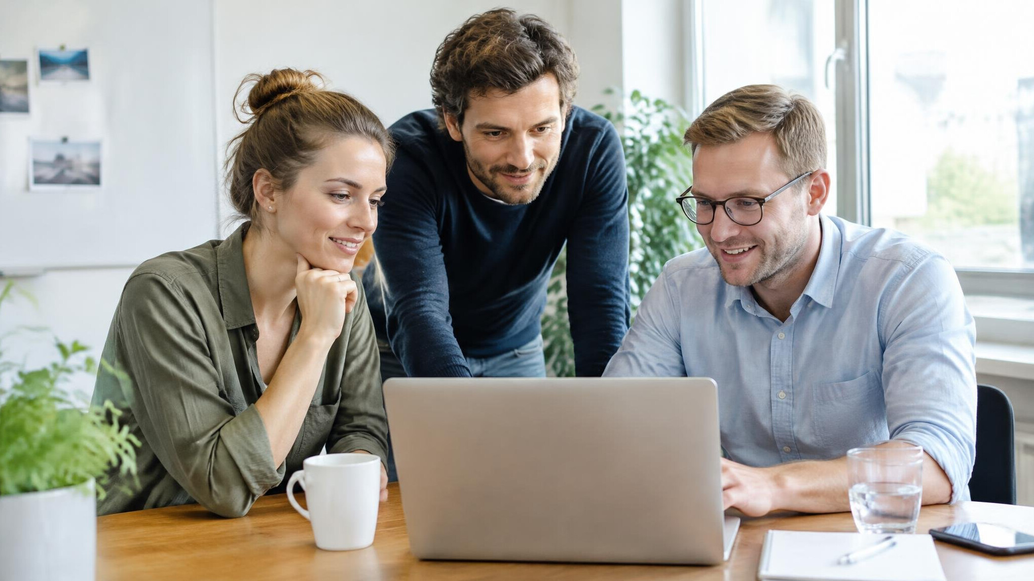 Small team gathered around a laptop in a meeting